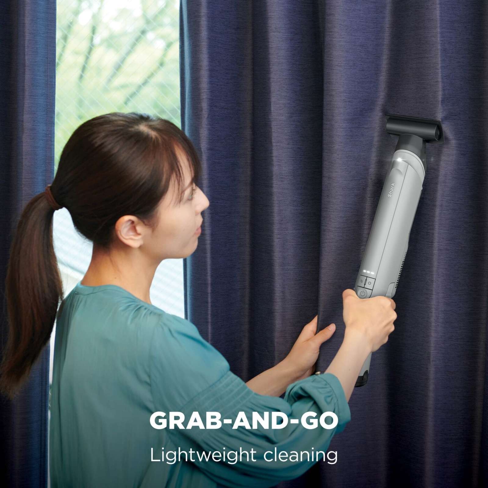 Shark WandVac Deluxe Pet Pro in use with the Duster Crevice Tool cleaning a curtain rail, captioned 'Grab-and-go, lightweight cleaning'