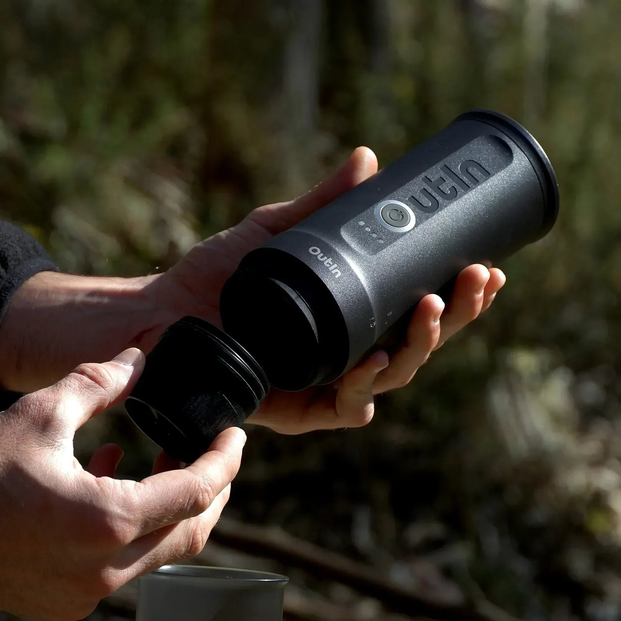 Outin Nano portable espresso machine in Space Grey with ground coffee, coffee capsules and a glass of espresso